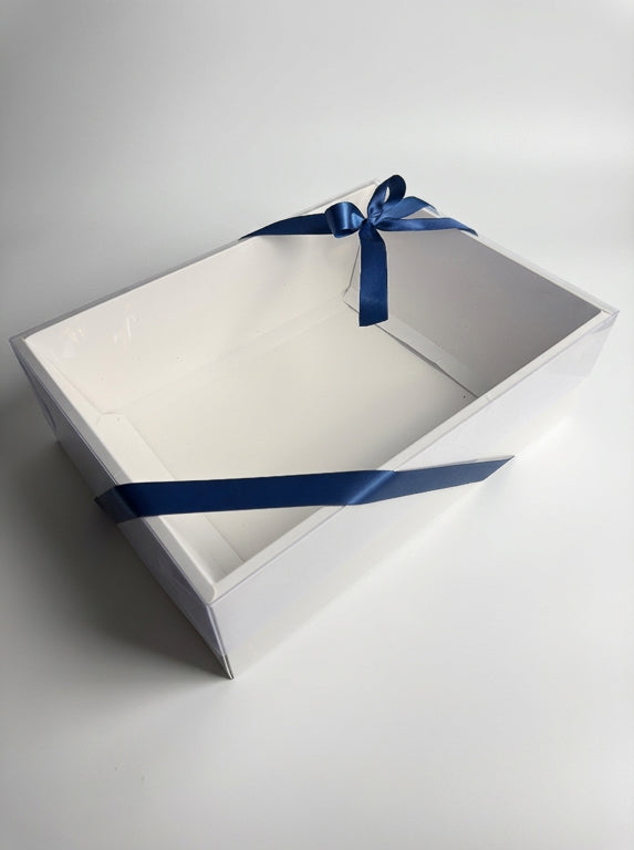 Boîte cadeau transparente fermée par un ruban bleu marine noué sur le dessus