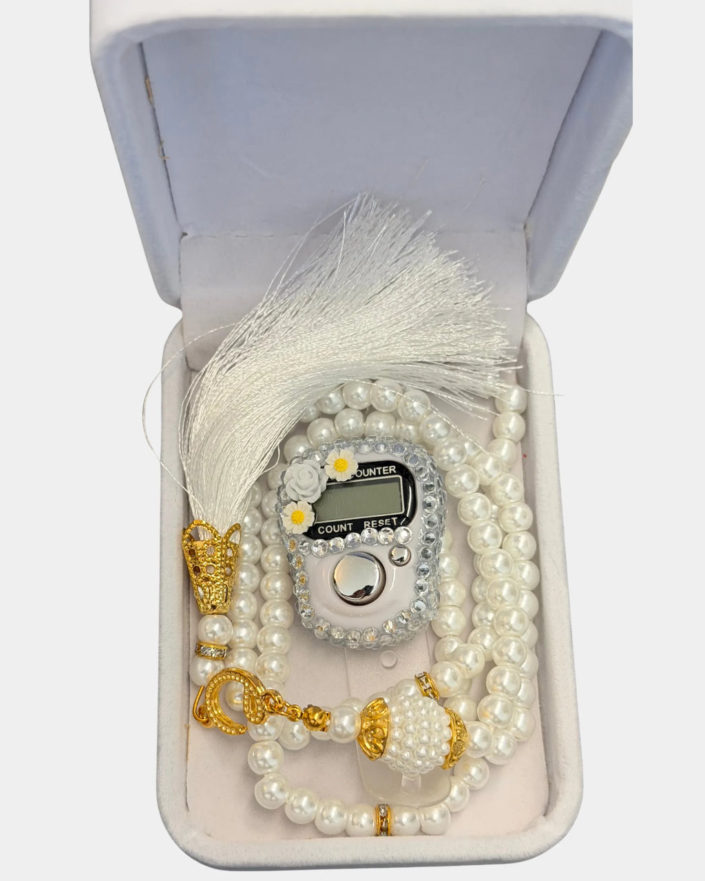 Détail du boîtier fleuri serti de strass, du fermoir doré et du pompon de soie blanche