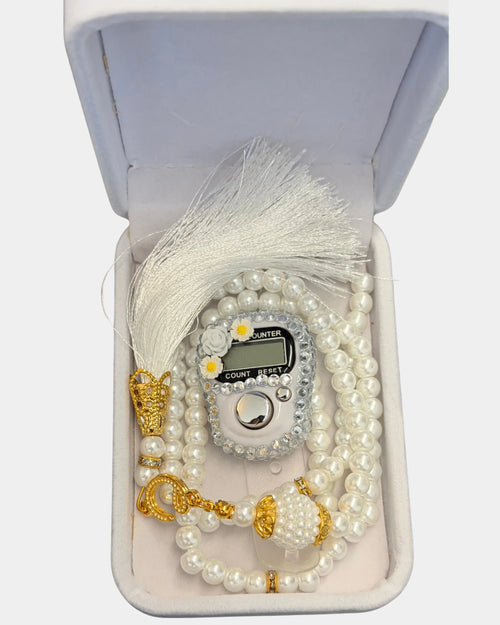 Détail du boîtier fleuri serti de strass, du fermoir doré et du pompon de soie blanche